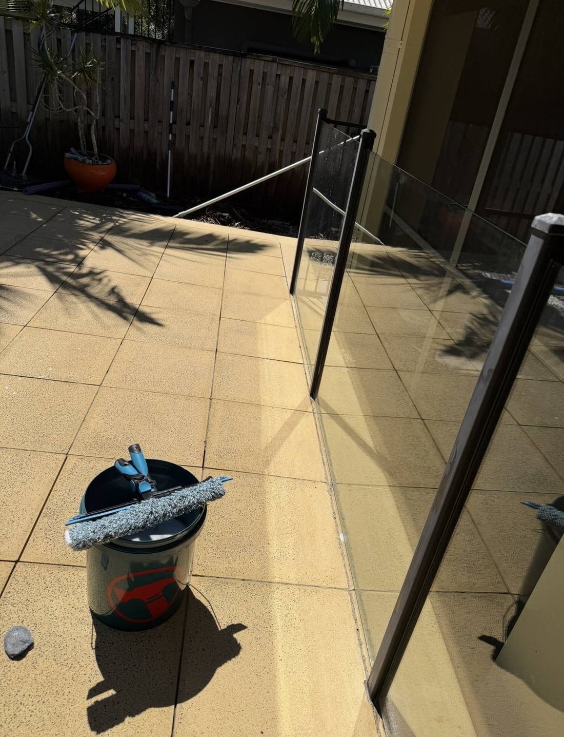 Glass pool fence cleaning kit set up beside a Gold Coast pool